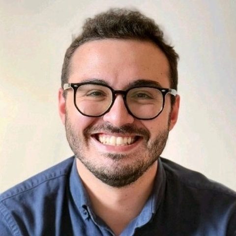 Artur Batissoco, fundador do Mural do Saber, sorrindo, de óculos e camisa azul